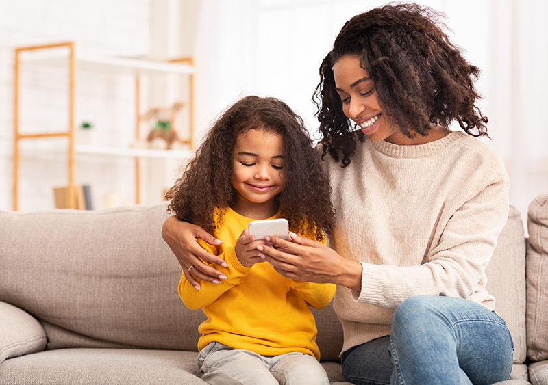 a mother teaches her child about dialing on a mobile phone